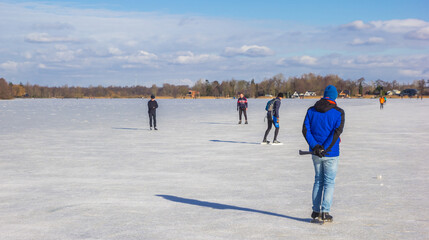 Man in blue coat skating on the lake in Paterswolde, Netherlands