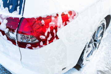 Hand washing with high pressure water in a car wash outside. The car is full of foam. The concept...