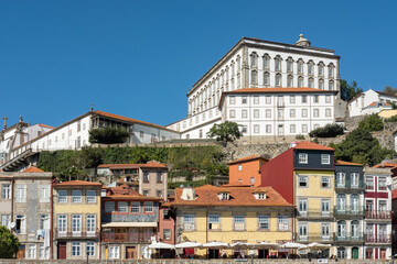 View of the terraced buildings located in the Ribeira neighborhood as seen from Douro River, small townhouses with large windows and ornate wrought iron balconies in city of Porto, Portugal