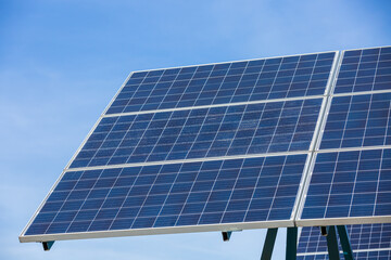 Obraz premium Solar cells panels. Solar farm on blue sky background. Photovoltaics solar cells panels in solar power station. Green energy from natural and Clean energy concept