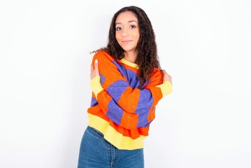 Charming pleased beautiful teen girl wearing knitted colourful sweater over white background...