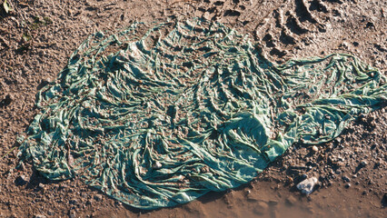 Bolsa de plástico y huellas de tractor en barro 