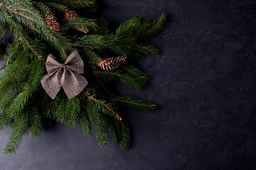 Christmas background. Spruce branches with cones on a dark table