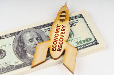 On the dollars lies a wooden model of a rocket with the inscription - economic recovery