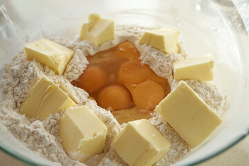 White wheat flour, butter and eggs in a bowl - ingredient for baking