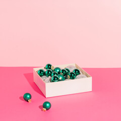 Green Christmas balls in a box on a pink background. Minimal Christmas concept