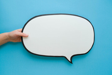Speech bubble in hand on a blue background. Comic cloud with a place for text