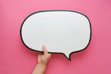 Speech bubble in hand on a pink background. Comic cloud with a place for text