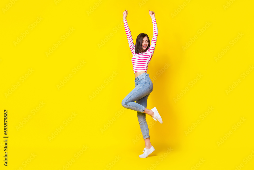 Poster Full size photo of nice gorgeous cheerful girl dressed striped shirt jeans white sneakers fists up isolated on yellow color background