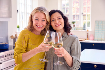 Portrait Of Same Sex Mature Female Couple Celebrating With Glass Of Wine At Home Together