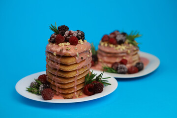 sweet delicious fragrant pink cupcakes in the shape of a heart and round with pink icing on top and decorated with blackberry raspberries and a sprig of rosemary on a blue background. for signage menu