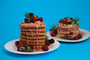 sweet delicious fragrant pink cupcakes in the shape of a heart and round with pink icing on top and decorated with blackberry raspberries and a sprig of rosemary on a blue background. for signage menu