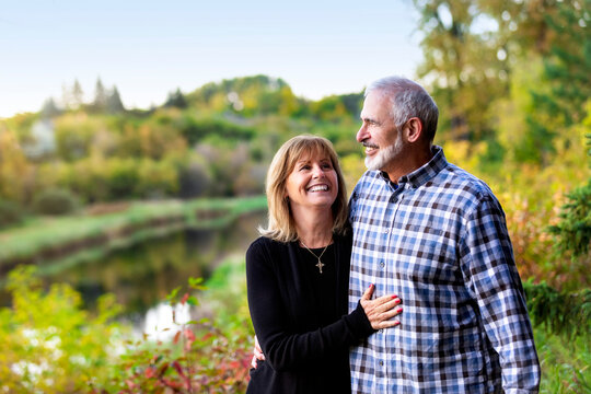 A mature couple enjoying quality time together while walking along a river in a city park on a warm fall evening; St. Albert, Alberta, Canada