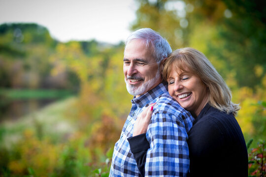 A mature couple enjoying time together and enjoying the sunset along a river in a city park on a warm fall evening; St. Albert, Alberta, Canada