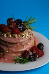 sweet delicious fragrant pink cupcakes in the shape of a heart and round with pink icing on top and decorated with blackberry raspberries and a sprig of rosemary on a blue background. for signage menu