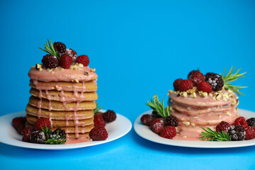 sweet delicious fragrant pink cupcakes in the shape of a heart and round with pink icing on top and decorated with blackberry raspberries and a sprig of rosemary on a blue background. for signage menu