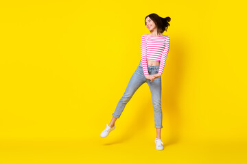 Fototapeta na wymiar Full size photo of pretty young woman dancing look empty space feel free wear stylish striped garment isolated on yellow color background