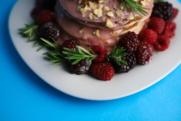 sweet delicious fragrant pink cupcakes in the shape of a heart and round with pink icing on top and decorated with blackberry raspberries and a sprig of rosemary on a blue background. for signage menu