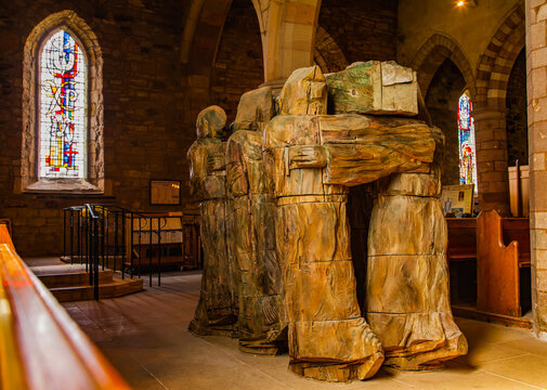 View from behind of a carved wooden statue depicting monks bearing the coffin of St. Cuthbert on their shoulders in the Lindisfarne Priory: Holy Island, Northumberland, England