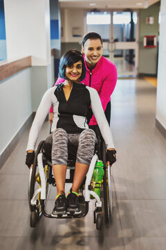 A paraplegic woman and her trainer pose for the camera while in a hallway in a recreational facility: Sherwood Park, Alberta, Canada