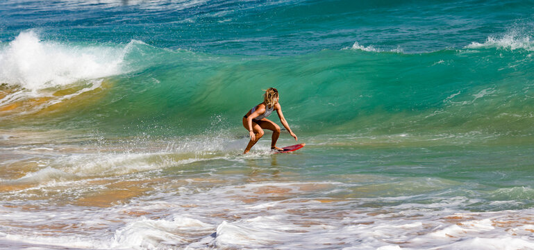 A young professional skimboarder riding a wave at Sandy Beach; Oahu, Hawaii, United States of America