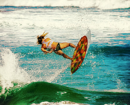 A young professional skimboarder riding a wave and performing trick at Sandy Beach; Oahu, Hawaii, United States of America