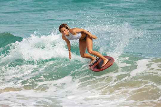A young professional skimboarder riding the crest of a a wave at Sandy Beach; Oahu, Hawaii, United States of America
