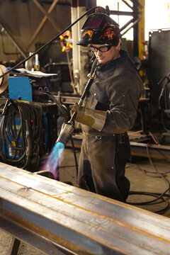 Tradesman pre-heating steel beam with a lift lug using a torch; Innisfail, Alberta, Canada