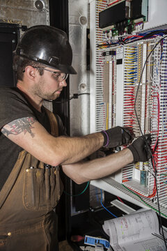 Electrician wiring a control panel; Innisfail, Alberta, Canada