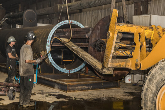 Tradesmen installing a line heater coil into line heater bath using a forklift; Innisfail, Alberta, Canada