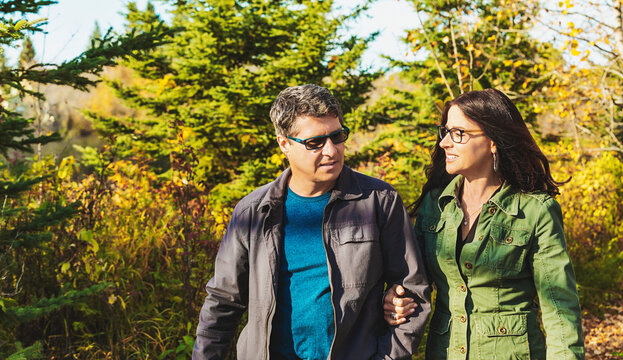 A mature married couple walking together and enjoying time together in a park during the fall season; St. Albert, Alberta, Canada