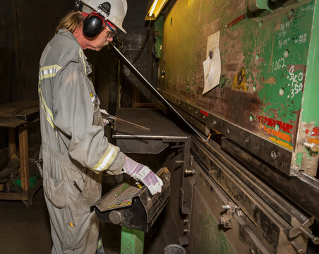 Tradesman operating brake to form a metal plate to a required shape; Innisfail, Alberta, Canada