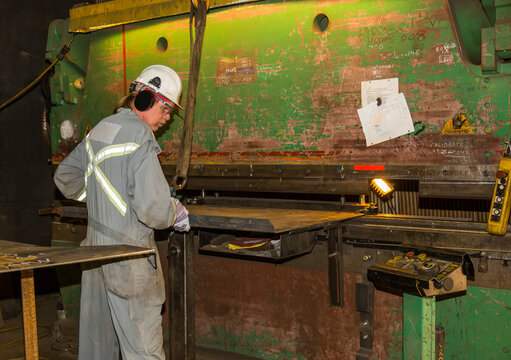 Tradesman operating brake to form a metal plate to a required shape; Innisfail, Alberta, Canada