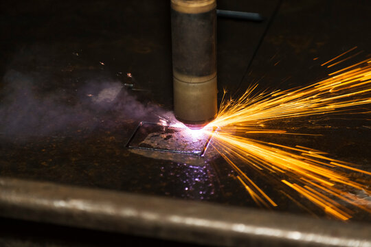 Sparks fly from a plasma cutter in a fabrication plant; Innisfail, Alberta, Canada