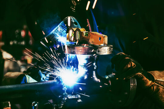 A journeyman welder attaching flanges to a pipe uses tack welding for pipe fitting alignment in a metal fabrication plant; Innisfail, Alberta, Canada