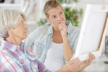 senior woman looks at photo in frame with daughter