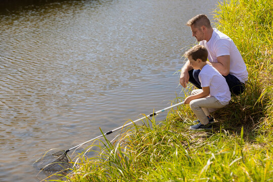 A father and son catching bugs in a stream in a city park during the fall season; Edmonton, Alberta, Canada