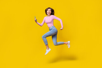 Fototapeta na wymiar Full length photo of stunning young woman hold telephone run influencer dressed trendy striped clothes isolated on yellow color background