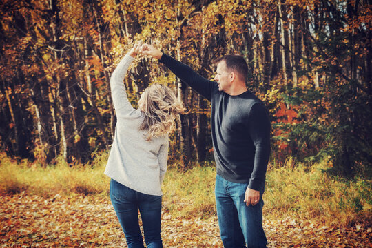 A married couple spending quality time together and dancing together outdoors in a city park during the fall season; St. Albert, Alberta, Canada
