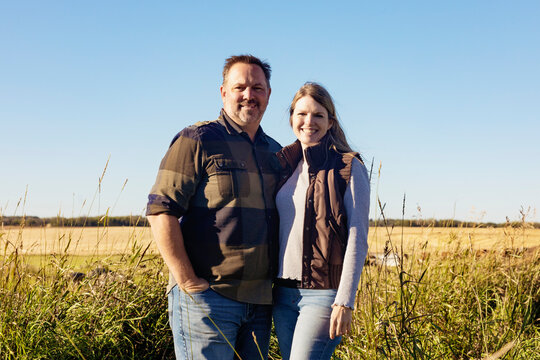 Portrait of a mature couple standing on their farmland; Alcomdale, Alberta, Canada