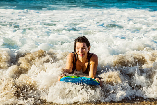 Close-up of a woman riding a wave on a bodyboard into the shore at D. T. Fleming Beach; Kapalua, Maui, Hawaii, United States of America