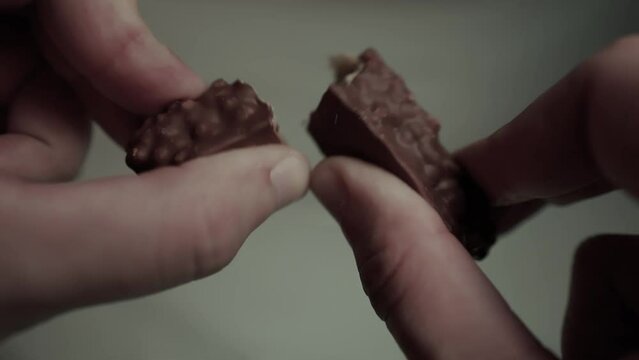 Hands break a bar of chocolate. Closeup.