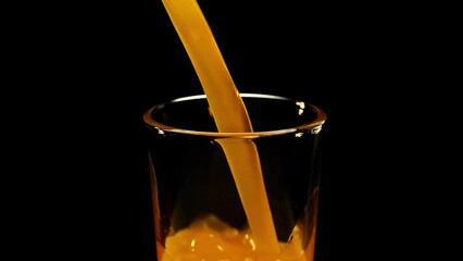 Pouring Orange Drink. Slow Motion. Pouring orange juice soda in glass in slow motion, black background