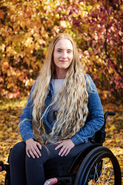 A young paraplegic woman in her wheelchair in a park on a beautiful fall day; Edmonton, Alberta, Canada