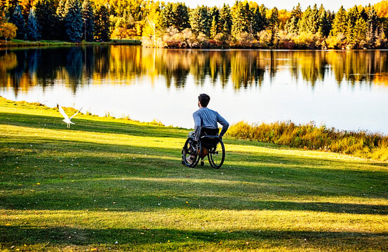 Young paraplegic man in a wheelchair outdoors in a park in autumn; Edmonton, Alberta, Canada