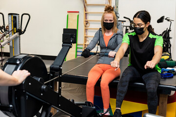 A paraplegic woman working out on a rowing machine with her trainers; Edmonton, Alberta, Canada