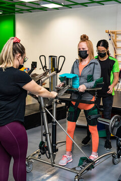 A paraplegic woman working out using an assisted walking machine with her trainers; Edmonton, Alberta, Canada
