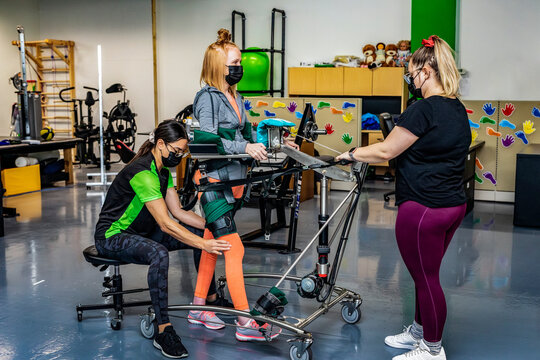 A paraplegic woman working out using an assisted walking machine with her trainers; Edmonton, Alberta, Canada