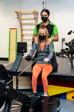 A paraplegic woman working out on a rowing machine with her trainer; Edmonton, Alberta, Canada
