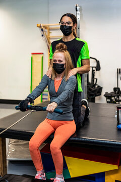 A paraplegic woman working out on a rowing machine with her trainers; Edmonton, Alberta, Canada